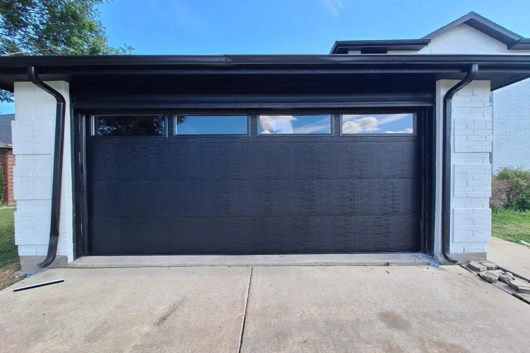 Freshly poured residential driveway in front of a dark garage door